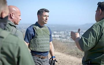 Group of four military personnel wearing green clothing talking out in the field